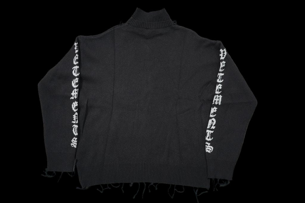 Vetements black destroyed anarchy turtleneck with white lettering on sleeves.