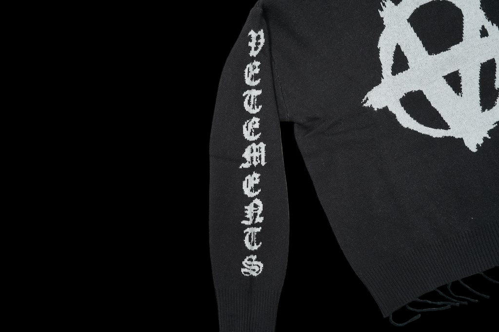 Black Vetements turtleneck with anarchy symbol and text on sleeve.