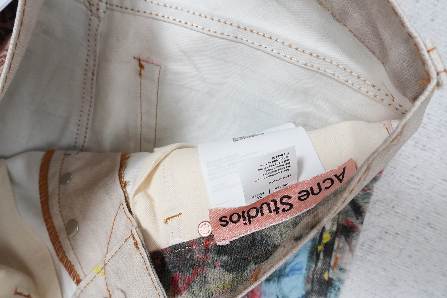 Acne Studios wide-leg jeans with trompe l'oeil print and pink logo tag.