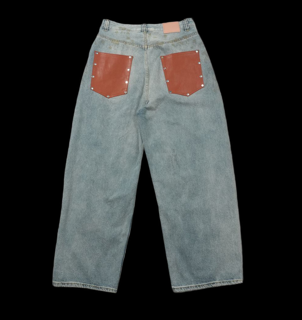 Acne Studios mud-dyed distressed wide-leg baggy jeans with brown leather back pockets.