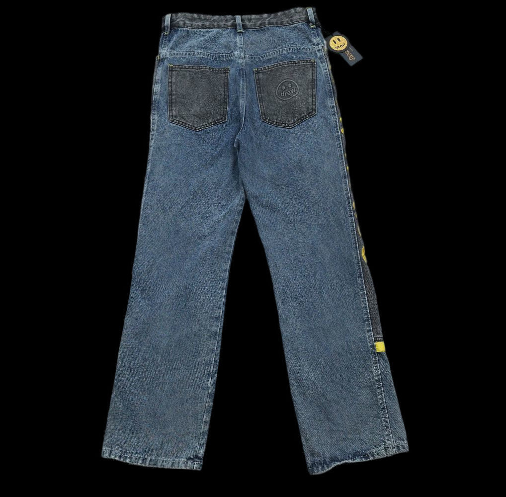 Drew House wide leg denim jeans with smiley face detail and yellow stripe accents.