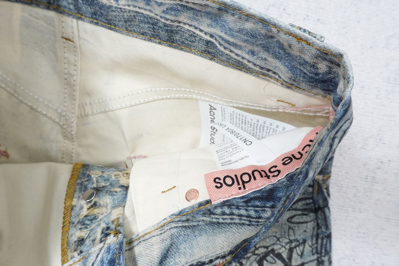 Acne Studios denim jeans with a torn scribble trompe l'oeil design.
