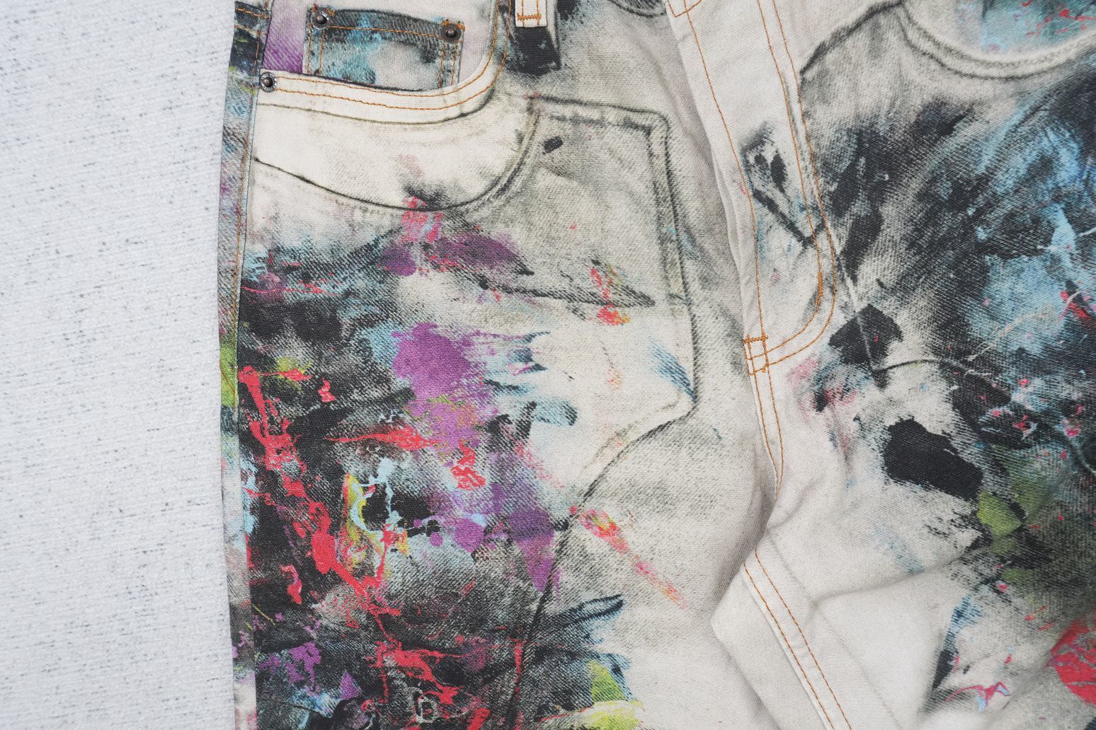 Acne Studios wide-leg jeans with a trompe l'oeil print in neutral tones.