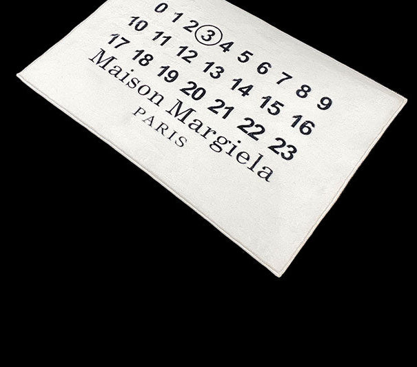 A plush Maison Margiela rug with a textured surface in neutral tones.