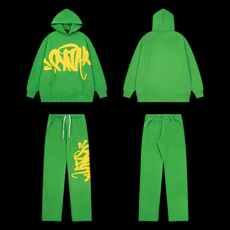 Green tracksuit with yellow graffiti-style graphic on the hoodie and left pant leg.