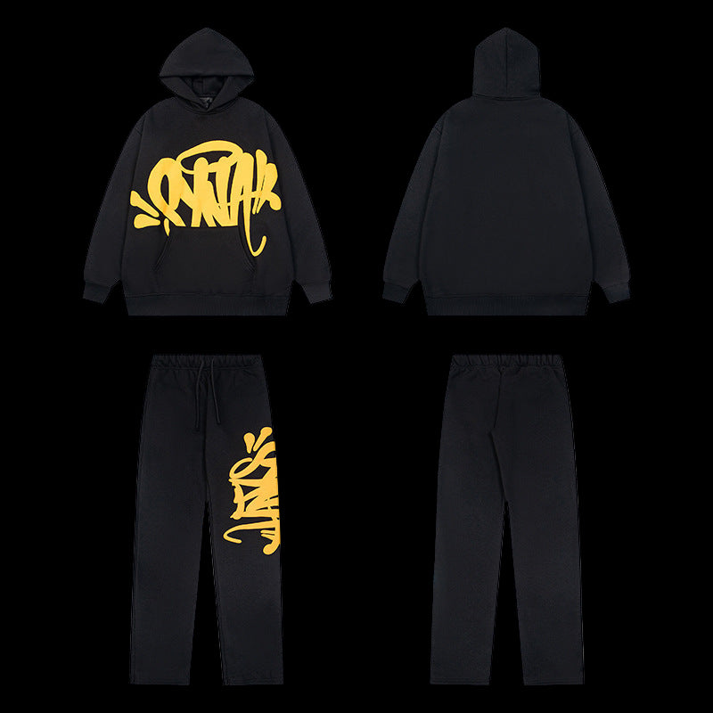 Black tracksuit with yellow graffiti-style logo on the hoodie and left pant leg.